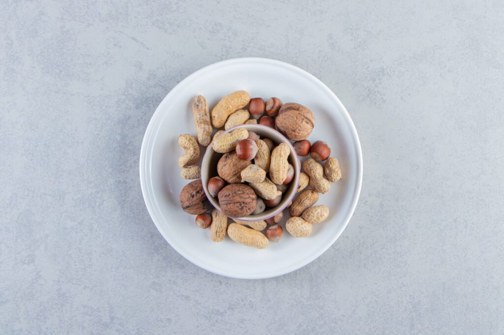 purple bowl full of various shelled nuts on stone background